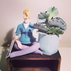 a figurine sitting on top of a wooden table next to a potted plant