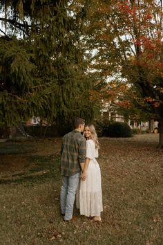 a man and woman standing next to each other in the grass