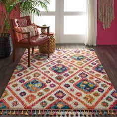 a living room with a chair and rug on the floor next to a potted plant