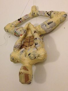 a stuffed animal made out of newspaper paper on a white wall next to a string