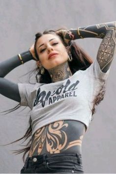 a woman with tattoos on her stomach and arms is holding her hair in the air