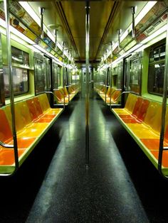 an empty subway car with orange and yellow seats on the inside, along with black flooring