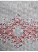 an embroidered piece of cloth with red and white designs