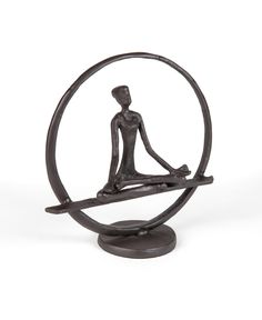 a bronze statue sitting in the middle of a circle with a person doing yoga on it