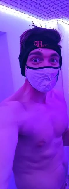 a shirtless man wearing a face mask in front of a mirror with purple light