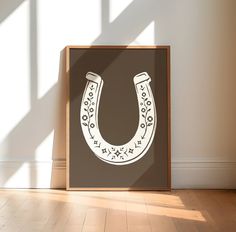 a wooden frame with a drawing of a horseshoe on the wall in an empty room