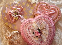 three pink and gold heart shaped hair clips on a lace doily covered tablecloth