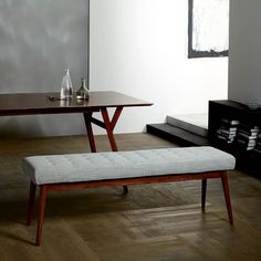 a bench and table in a room with wooden floors, white walls and wood flooring