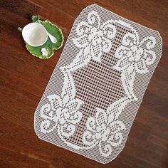 a white doily sitting on top of a wooden table next to a cup and saucer