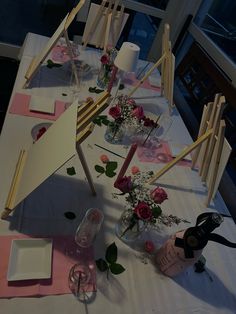 a table set up for a party with flowers in vases and place settings on it