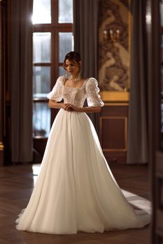 a woman in a white wedding dress is posing for the camera with her hands on her hips