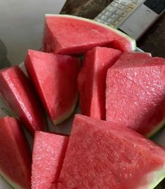 slices of watermelon on a plate with a remote control in the back ground