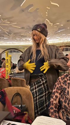 a woman wearing yellow gloves standing in front of a table