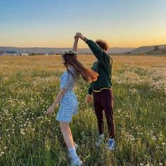 two people standing in a field holding hands