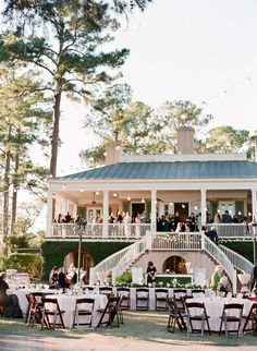 people are sitting at tables in front of a large house with white tablecloths