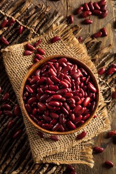 a wooden bowl filled with red beans on top of a table