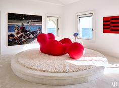 a living room with two red chairs and a painting on the wall