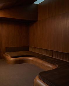 a curved bench in the corner of a room with wood paneling on the walls