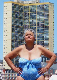 a woman in a blue swimsuit standing on the beach with her hands on her hips