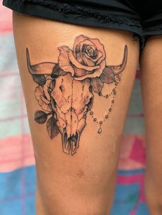 a woman's thigh with a cow skull and roses on it