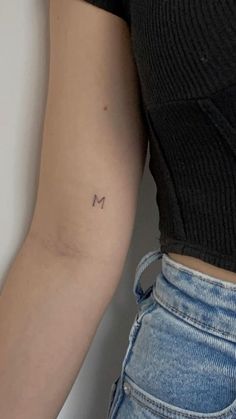 a woman's arm with the letter m tattooed on it