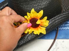 a person holding a sunflower on top of a hat