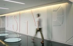 a blurry photo of a man walking past a glass wall with the word design on it