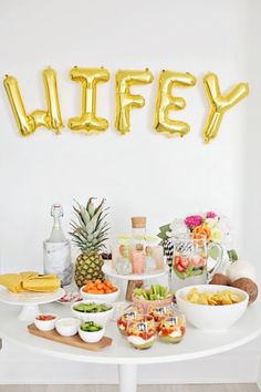 a table filled with food and balloons that say'wifey'in gold letters