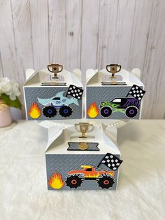 three boxes with monster trucks painted on the front and sides, sitting on top of a white furnishing