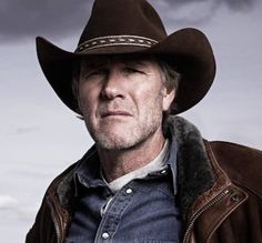 a man wearing a cowboy hat standing in the desert