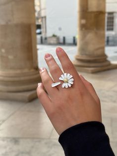 This handmade adjustable ring features a charming white daisy design, meticulously crafted to capture the essence of a blooming flower. The daisy petals are delicate and smooth, surrounding a golden coloured center that adds a touch of elegance and sparkle. The ring band, designed to look like a daisy stem, wraps comfortably around the finger, completing the floral theme.  Perfect for nature lovers and those who appreciate unique, artisanal jewelry, this ring brings a fresh and whimsical touch t White Daisy-shaped Jewelry For Spring, White Daisy-shaped Spring Jewelry, White Flower Jewelry With Sunflower Design, White Flower-shaped Jewelry With Sunflower Design, White Flower Ring For Spring, White Sunflower Design Flower Jewelry, Spring White Flower Ring, Spring White Flower Shaped Ring, White Flower Shaped Anniversary Ring