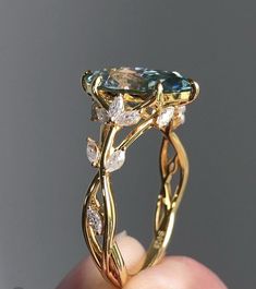 someone is holding up a fancy ring with an aqua blue stone