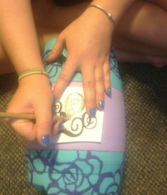 a woman is sitting on the floor with her hand on top of a blue suitcase