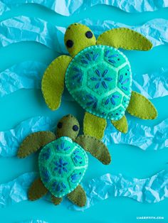 two felt sea turtles sitting on top of blue paper