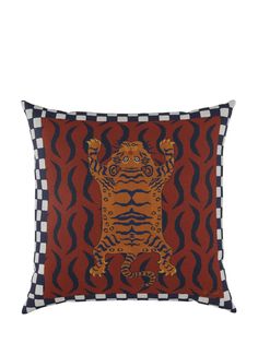 a red and black pillow with an orange tiger on it's back, in front of