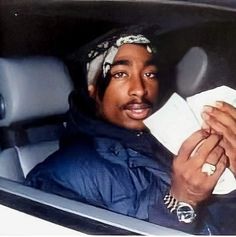 a man sitting in the back seat of a car holding a napkin and looking at the camera