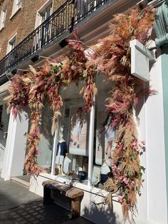 an outside view of a store front decorated with fake flowers and plants on the windows