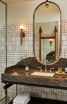 a bathroom sink sitting under a large mirror next to a walk in shower with tiled walls