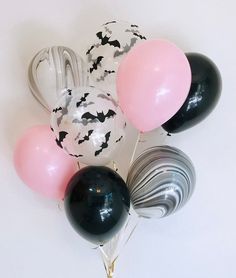 a bunch of balloons that have bats on them and some are black, white, and pink