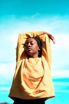 a woman with her hands on her head and wearing a yellow shirt over her shoulders