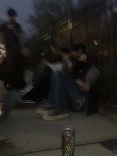 some people sitting on the ground and one is holding a can of soda in his hand