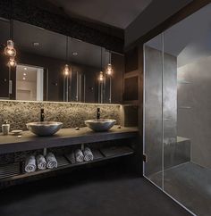 a bathroom with two sinks, mirrors and lights on the side of the shower stall