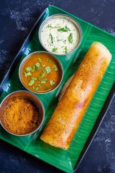 a green plate topped with different types of food next to bowls of dips and sauces