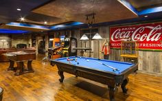 a game room with pool table, foo - pong tables and coca cola signs