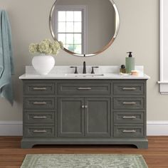 a bathroom vanity with a round mirror above it and a rug on the floor next to it