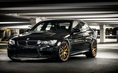 a black car with gold rims parked in a parking garage