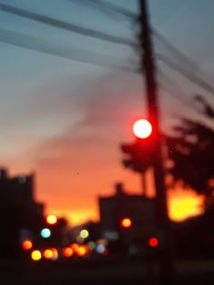 the traffic light is red in the city at night time as the sun goes down