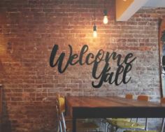 a brick wall with the words welcome gate painted on it and chairs in front of it