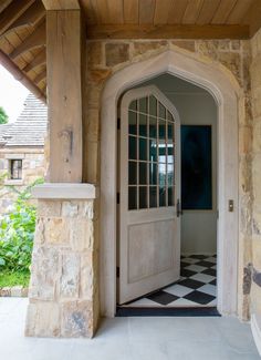 an open door to a stone house with black and white checkered flooring