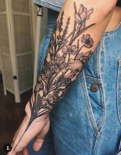 a woman's arm with flowers and leaves tattooed on the left side of her arm